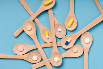 Wooden spoons  filled with various pills and capsules of different colors . Assorted pharmaceutical...