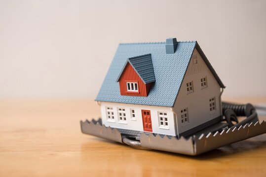 House in rat trap on wooden table white wall background. Real estate, property, land, rental, mortgage closing scams concept. Protect money from real estate scams when buying, rental a home.