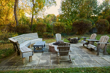 Patio furniture, chairs, and firepit in autumn. Photograph of a hardscaped backyard. 