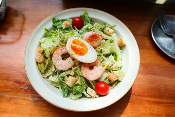 close up of salad with boiled egg, shrimp, cherry tomato and avocado cheese sauce on a white plate