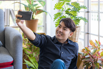 A handsome asian man relax and take selfie shot in living room in his house