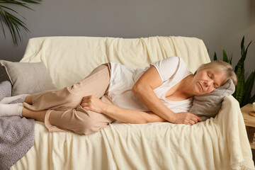 Peaceful older woman sleeping relaxing on comfortable couch with closed eyes calm lazy mature female enjoying free time on weekend resting in living room