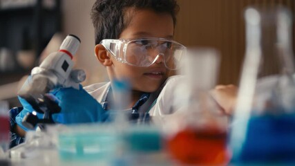 Schoolboy in protective glasses looking into microscope, science class, S.T.E.M.