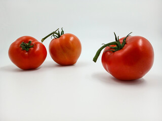 Red tomato with green branches and leaves. The vegetable from the farm. A fresh juicy product. Sauces, ketchup are made from it. Culinary theme, catalog, food packaging for a supermarket or blog.