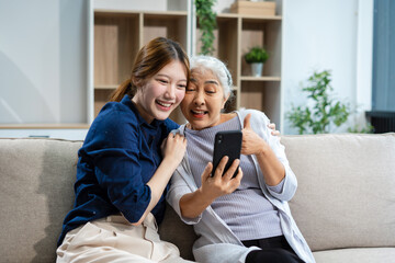Happy granddaughter taking care of her grandmother sitting on the sofa.