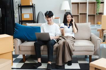 Obraz premium Successful young couple is moving to a nice new place, around boxes with their belongings. The room is very bright and bright, they are wearing casual clothes.