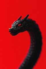 Obraz premium Striking Black Dragon Sculpture on Vivid Red Background