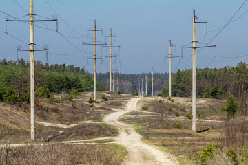 Power lines stretching across rural landscape with dirt road
