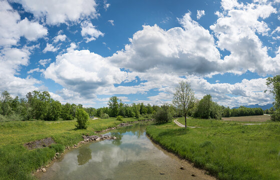Mangfall river and green riverside with trees, mountain view. blue sky with clouds