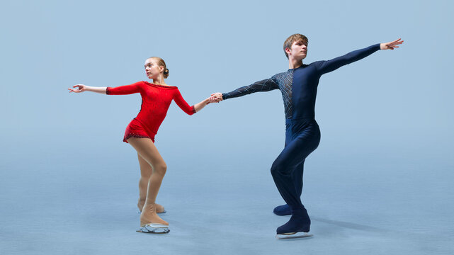 Dynamic photo of figure skating duo in synchronized pose, highlighting their competitive spirit and precision against cold blue background. Concept of winter sport, elegance and grace, championship.
