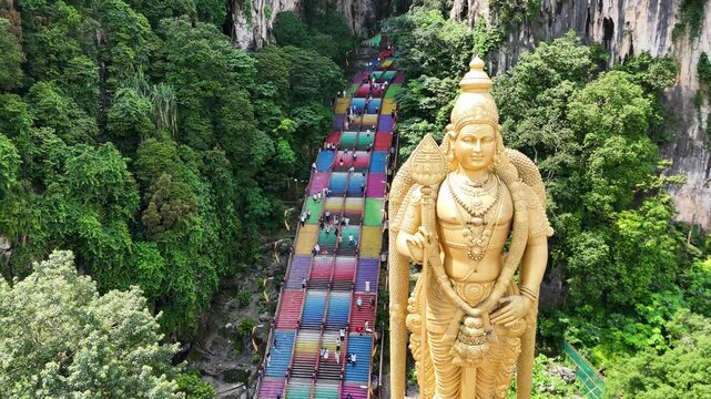 Majestic statue of Lord Murugan at Batu Caves, near Kuala Lumpur, Malaysia, with vibrant colorful  stairs in the background.