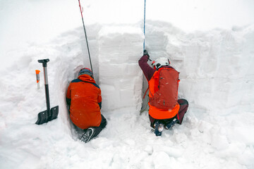 A mountain safety experts in vibrant gear examines the snow wall's secrets, probing for vital avalanche information