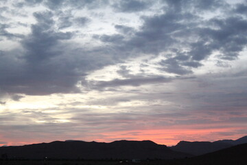 A wide shot of a cloudy sky at sunrise or sunset over a mountain range