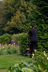 Gardener Mowing Lawn in Lush Green Garden. High quality photo