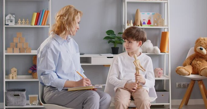 Child therapist, small preschooler boy, teacher, testing, evaluate, sharing problems. Caring attentive adult having trustful conversation, treating emotional and behavioral professional psychology