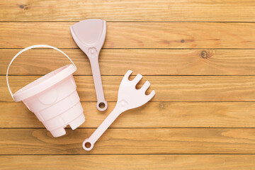 Cute toys for playing with sand on wooden background, top view