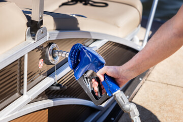 Man refueling boat at marina. Gas pump nozzle filling pontoon party boat fuel tank.