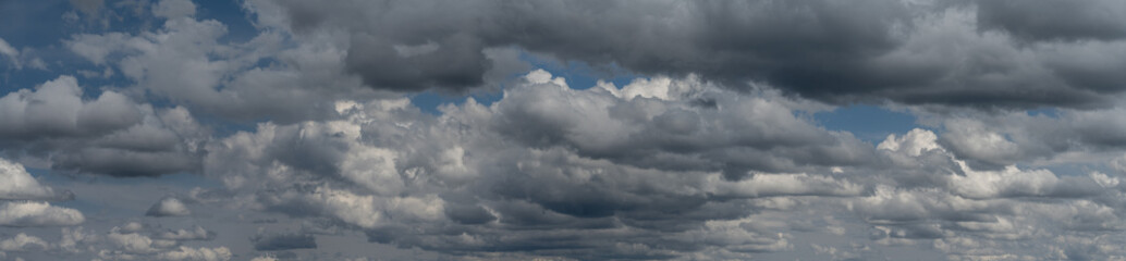 Panorama of building gray summer storm clouds in a blue sky. Only sky in frame
