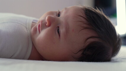 Baby lying on bed, eyes open and gazing calmly. serene and peaceful moment capturing the early stages of childhood in a cozy, nurturing indoor environment