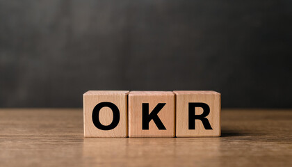 Wood cubes with abbreviation text OKR on wooden table. Objectives and Key Results.