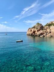 small boat on clear blue water with rocks