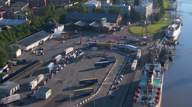 Aerial view showcasing Turku harbor in Finland. Trucks and cars line up, awaiting ferry boarding while a large white ship rests at the pier