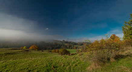 Autumn meadows and foggy valleys near mountain cottages near Jaworki village
