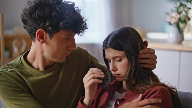 Loving husband consoling wife in upset mood indoors. Caring man giving support