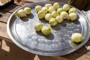 Whole peeled onions are lying on a stainless steel tray. Preparing pilaf.
