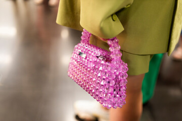 A woman in a lime-green blazer holds a pink plastic bag. Close-up.