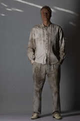 Portrait of an elderly man in dirty clothes on a white background