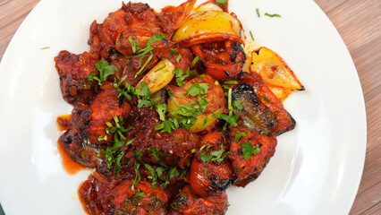 Plate of beautifully arranged chicken tikka masala, showcasing juicy pieces of grilled chicken, colorful bell peppers, and aromatic spices. garnish with fresh cilantro and a drizzle of tangy sauce.