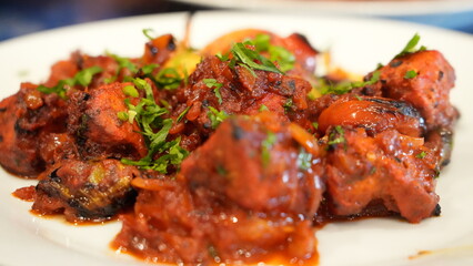 Colorful dish a spicy tomato-based stew featuring tender chunks of meat or vegetables with vibrant bell peppers and garnished with fresh cilantro.