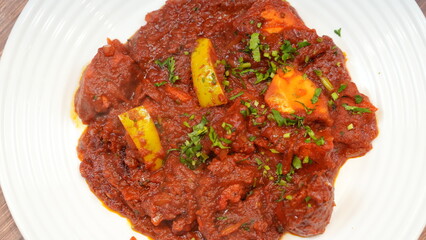 Colorful dish a spicy tomato-based stew featuring tender chunks of meat or vegetables with vibrant bell peppers and garnished with fresh cilantro.