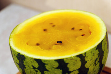 Slices of vibrant yellow watermelon are artistically displayed on a rustic wooden cutting board