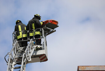 two Firefighters on the basket of the ladder truck during the intervention to recover the injured...