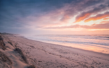 The beautiful pastel colors of the sunset are reflected on the wet sand of Rodanho beach in Viana do Castelo, Portugal, creating a magical atmosphere