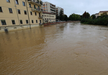 Obraz premium brown river overflowing and lapping at houses after a torrential downpour