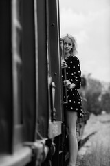 Portrait of a young beautiful blonde girl on the railway tracks. Black and white photo.