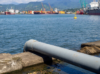 Pipe for draining sewage into the sea. Industrial zone. Environmental problem. Pipe leads into water.