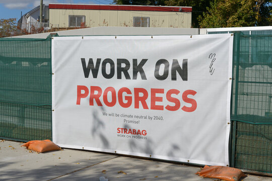 Strabag banner with slogan "Work on Progress" pinned to a construction site barrier fence on Eglinton Avenue West in Toronto, Canada