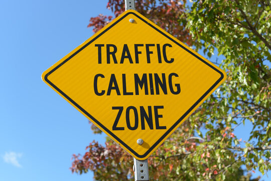 traffic calming zone sign on a blue sky with trees in autumn