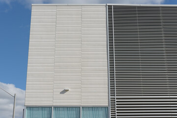 building facade (prefab cement panels with texture, ventilation louvres, glass windows, and sky...