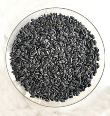 Organic sunflower seeds on a round plate on a white background. Texture or background concept. Many sunflower seeds.