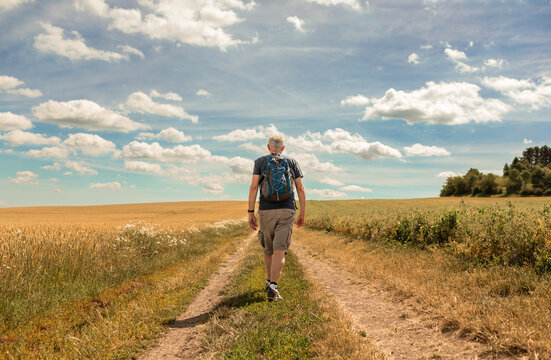 Senior male traveller hiking walking down country road