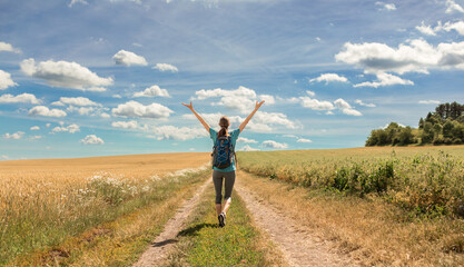 Happy joyful woman hiker traveler walking down country road 
