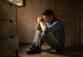 Young man praying hands folded sitting at home in bedroom, religious belief, prayer concept 
