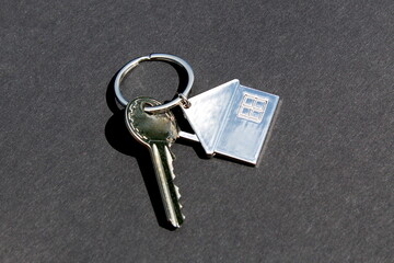 Iron keys to the apartment with a keychain lie on a black background.	