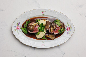 Appetizing medallions with mushrooms and mashed potatoes with sauce.