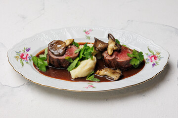 Appetizing medallions with mushrooms and mashed potatoes with sauce.